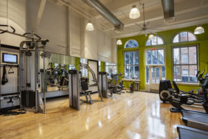 Fitness center with weights and cardio equipment at Chocolate Works Old City apartments